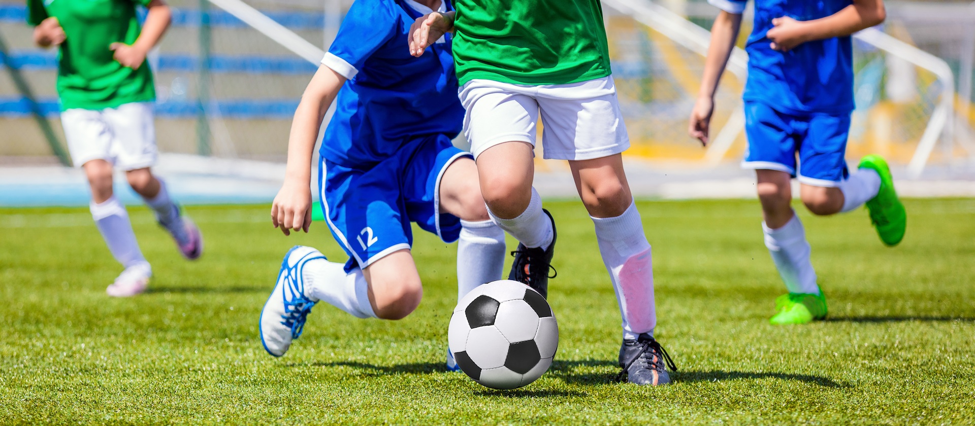 Running Soccer Football Players. Footballers Kicking Football Match game. Young Soccer Players Running After the Ball. Soccer Stadium in the Background